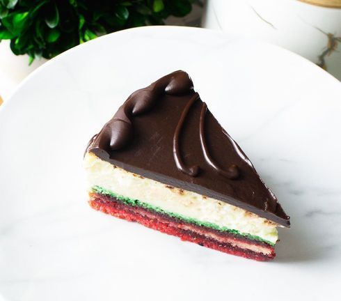 Slice of layered chocolate cake with green and red filling on a white plate