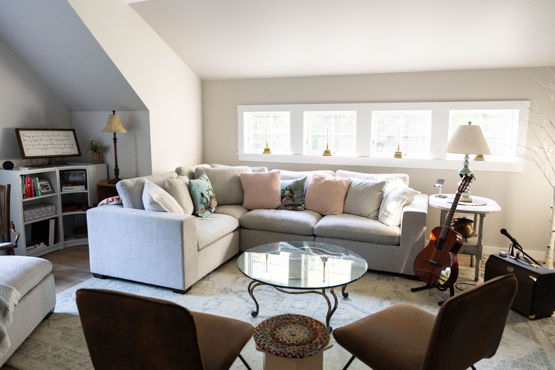 Cozy living room with sectional sofa, coffee table, and windows. Acoustic guitar and microphone on right.