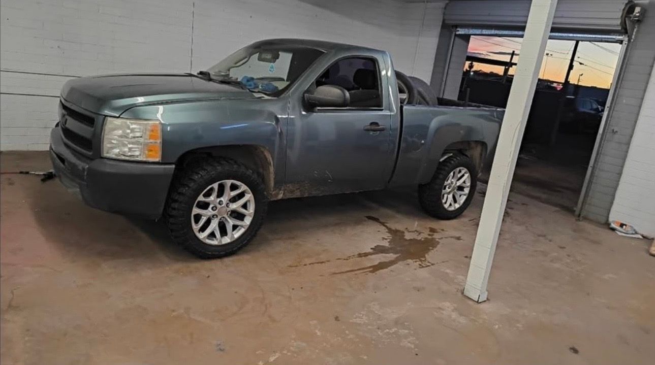 Gray pickup truck parked in a covered garage, with a white post in front of it.
