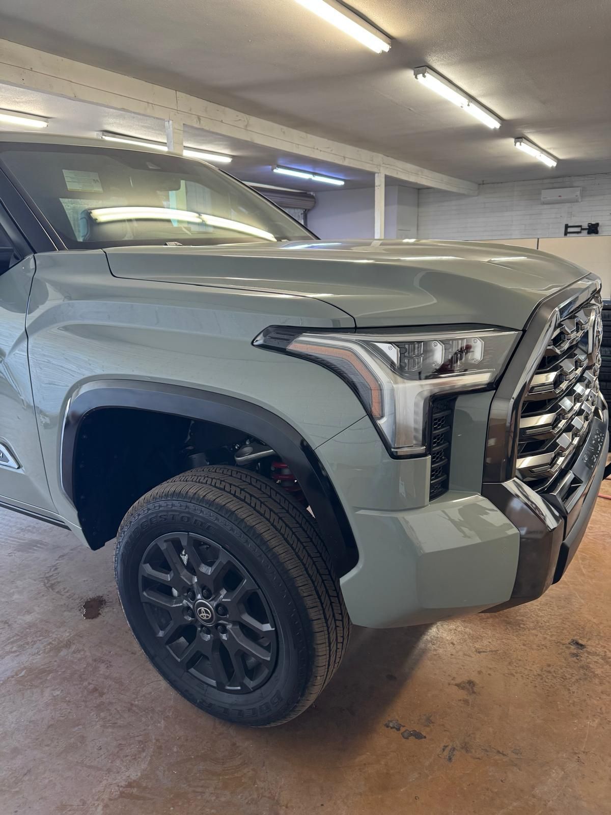 Gray pickup truck parked indoors, front-left view in a garage.
