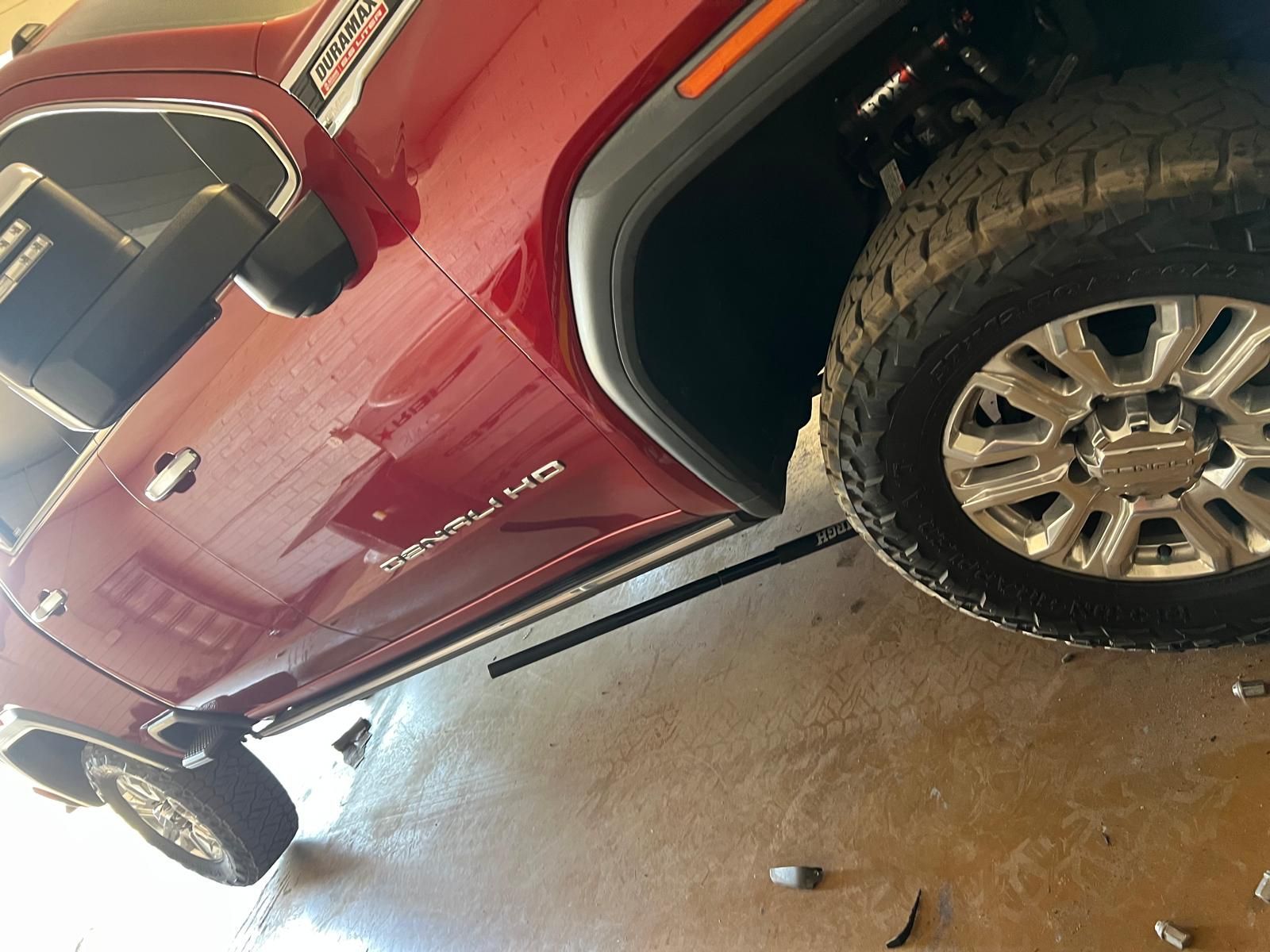 Red pickup truck parked in a garage, with a tire and wheel visible.