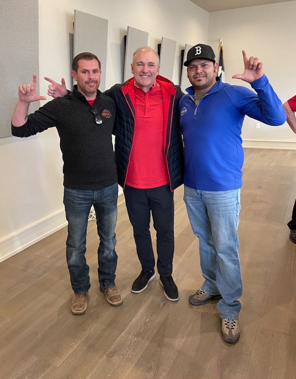Three people stand in a room posing with 