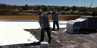 Two workers applying paint on a roof