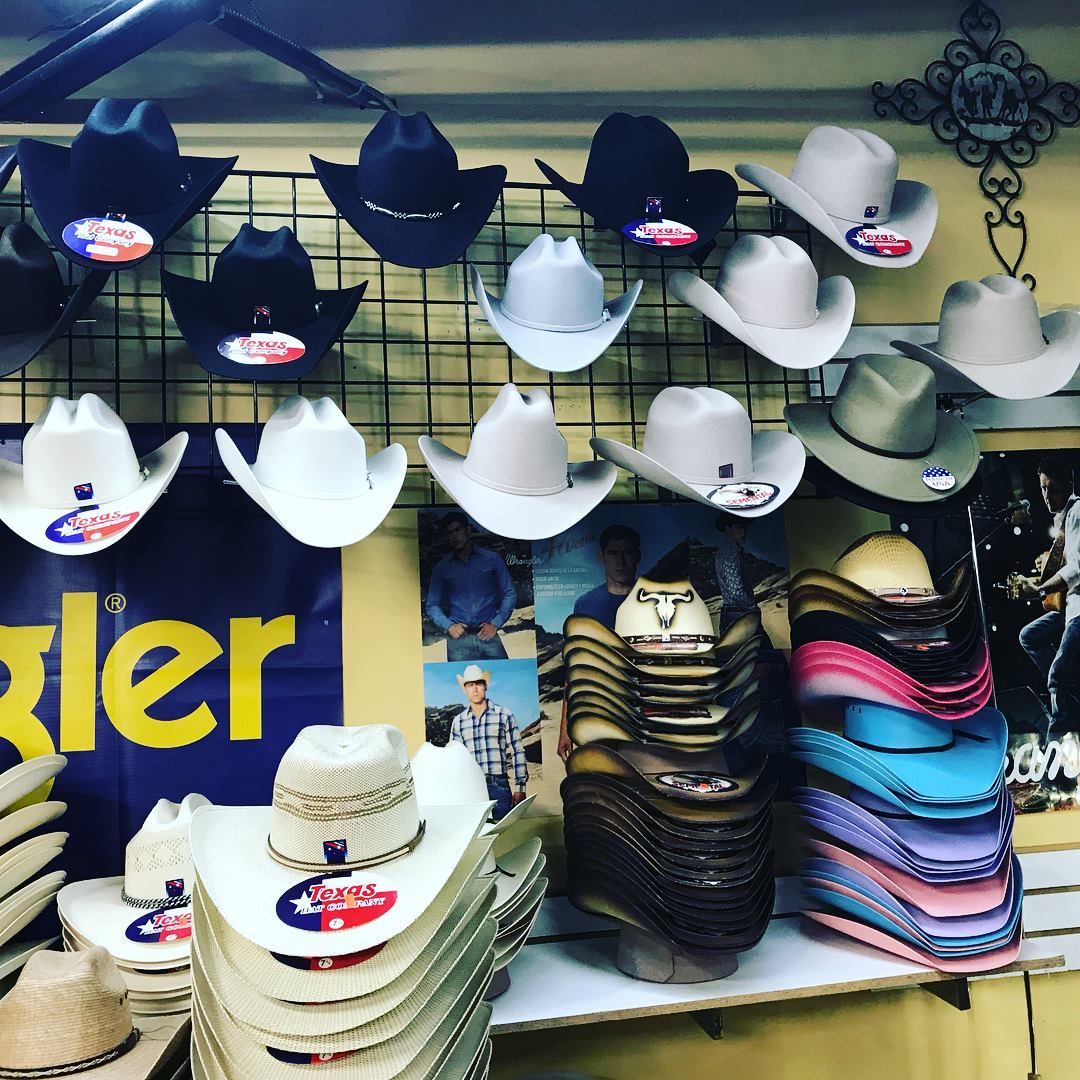 A bunch of cowboy hats are hanging on a wall in a store