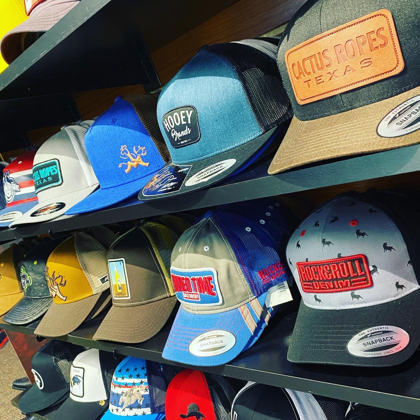 A shelf filled with a variety of hats including one that says cactus ropes