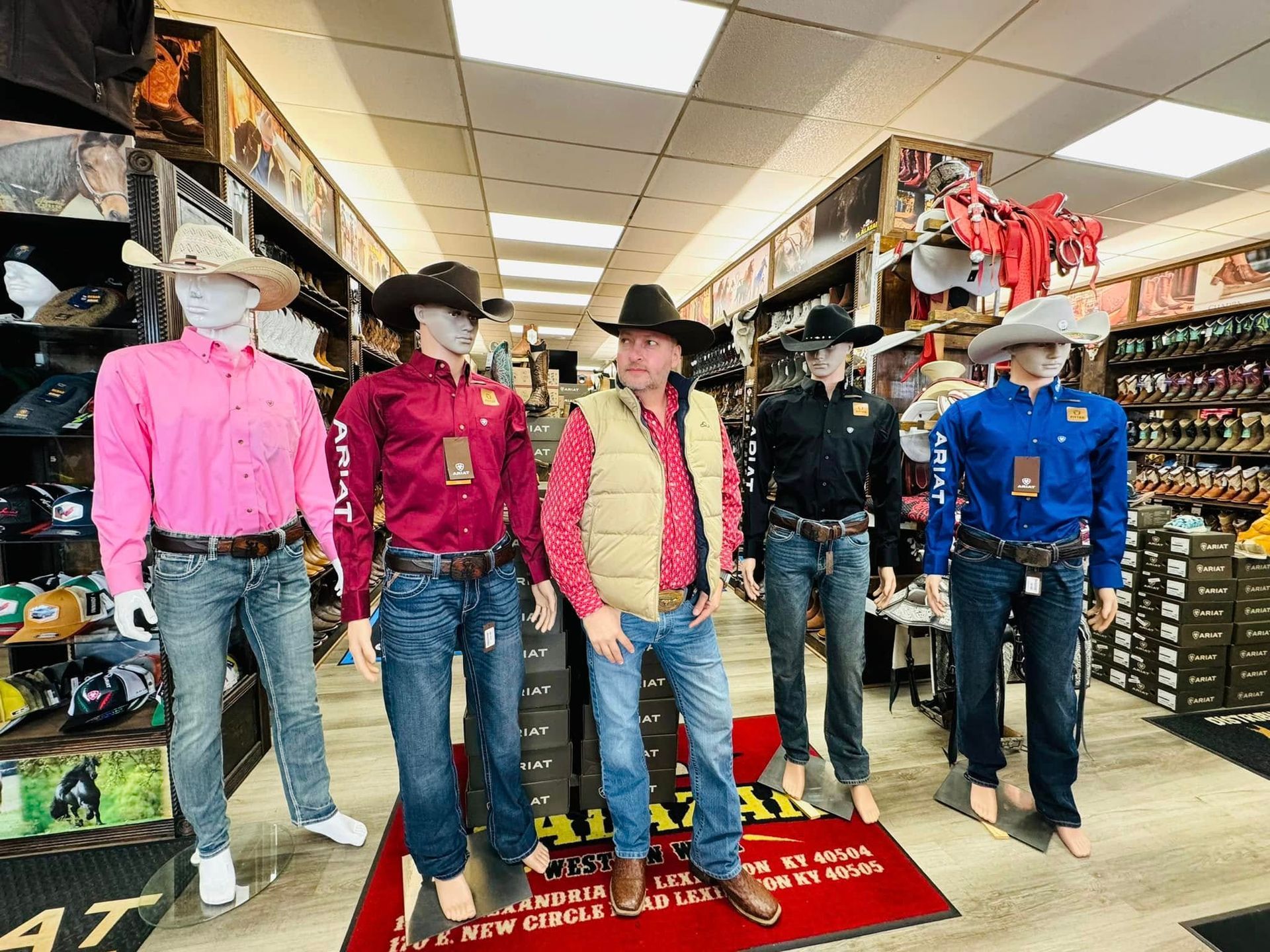 A man in a cowboy hat is standing next to a group of mannequins in a store.