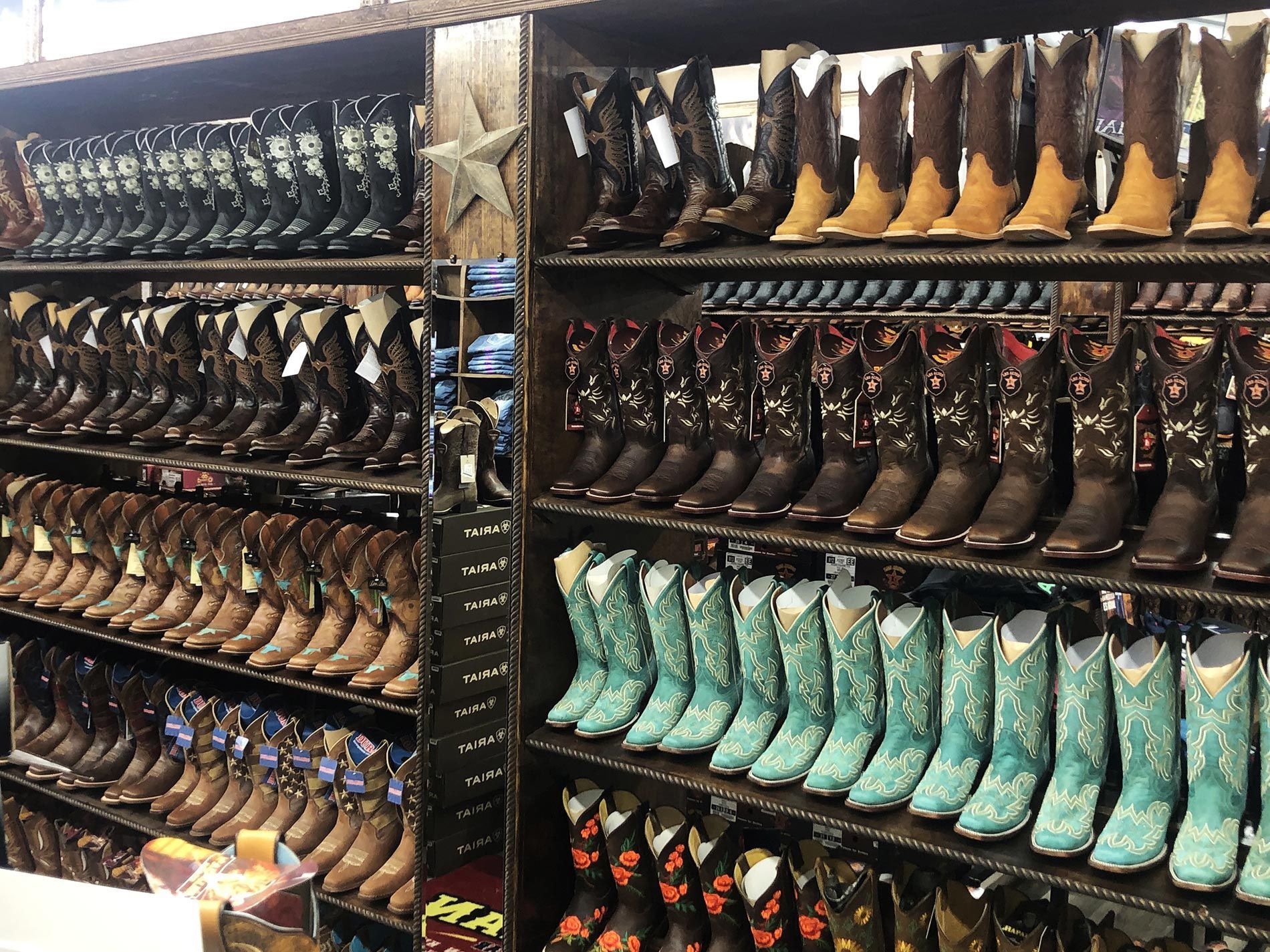 A row of cowboy boots are lined up on shelves in a store.