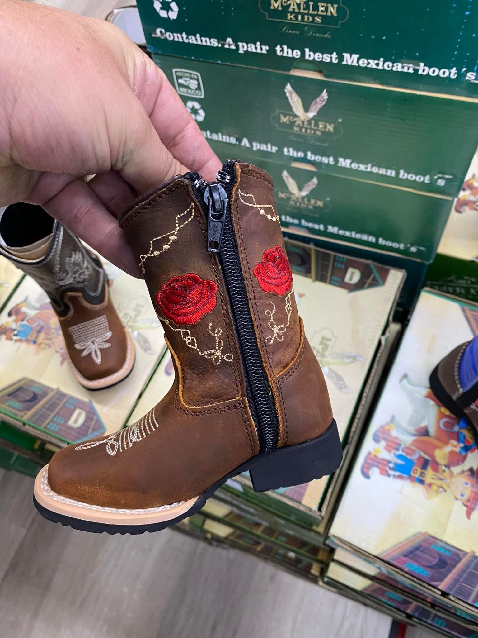 A person is holding a pair of cowboy boots in their hand.