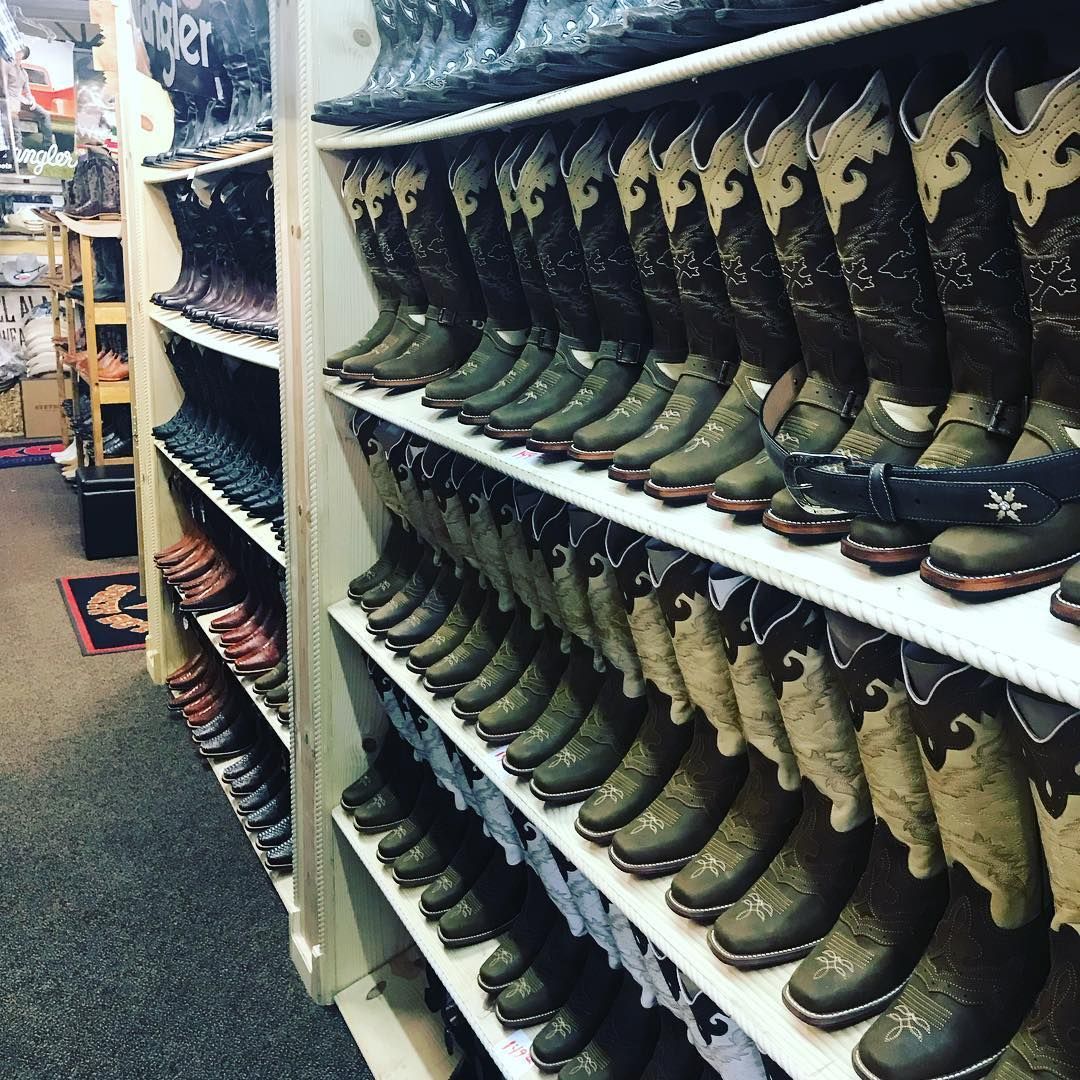 A row of cowboy boots are lined up on shelves in a store.