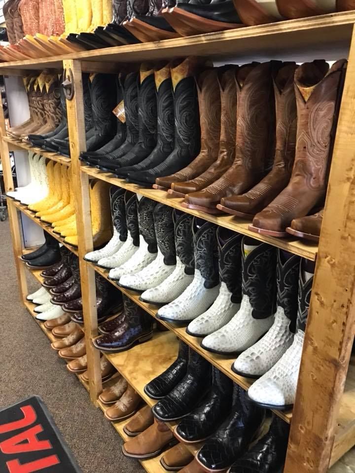 A row of cowboy boots are lined up on shelves in a store.