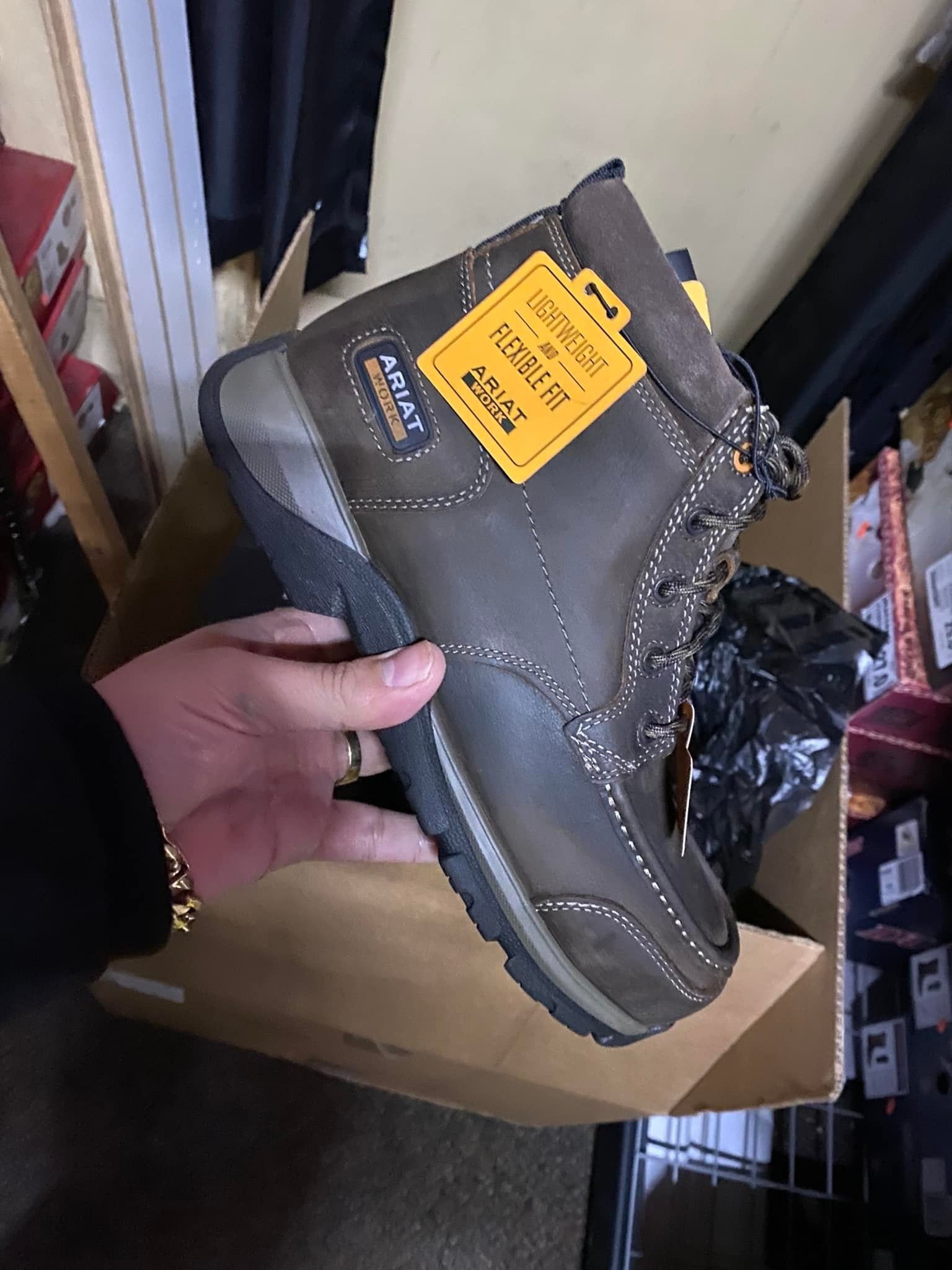 A person is holding a pair of brown boots in their hand.