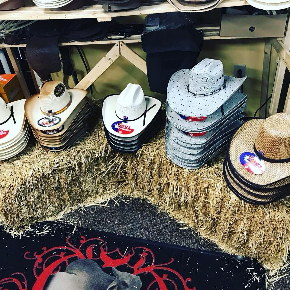 A bunch of cowboy hats are stacked on top of hay