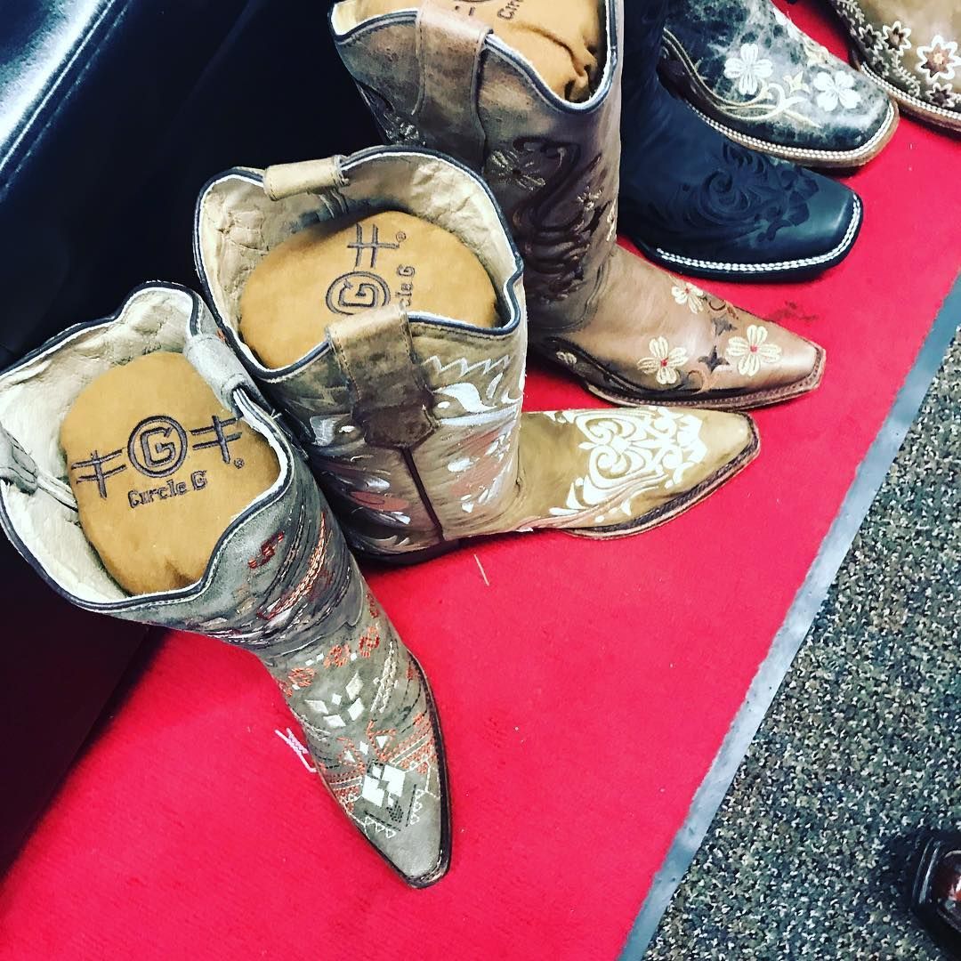 A pair of cowboy boots sitting on a red carpet