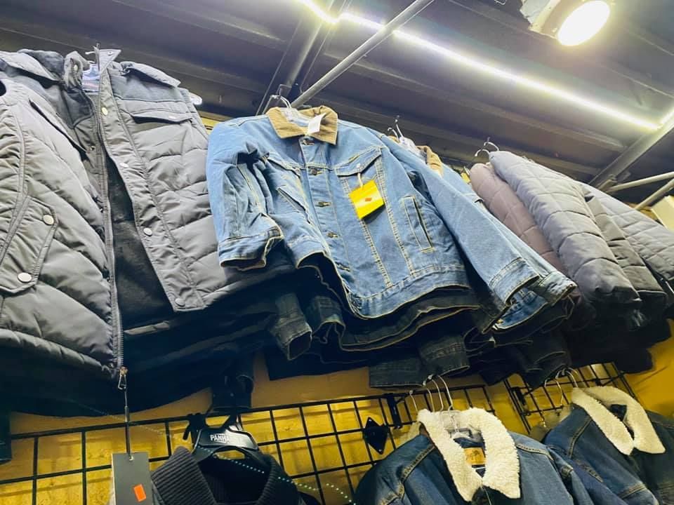 A bunch of jackets are hanging on a rack in a store.