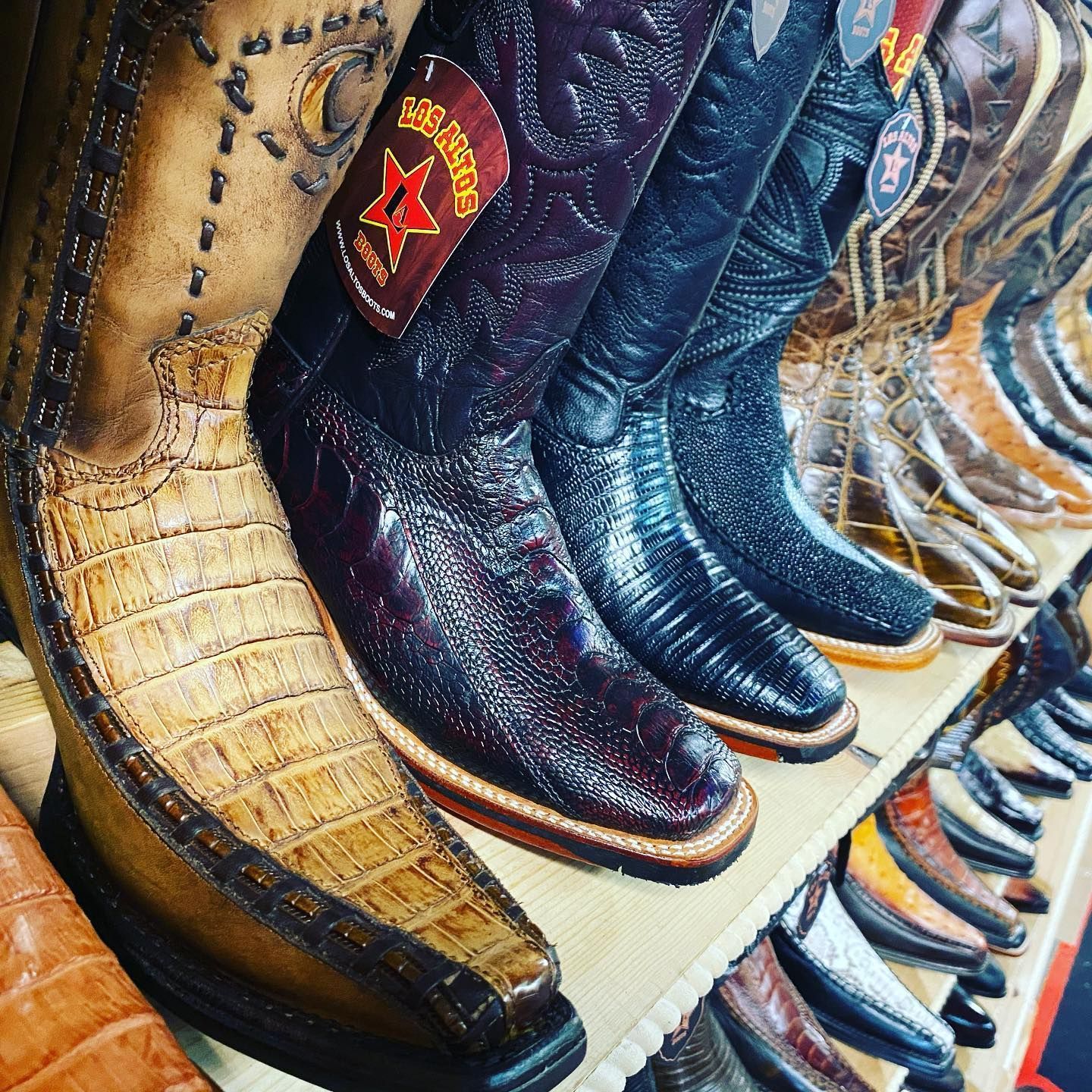 A row of cowboy boots are lined up on a shelf in a store.