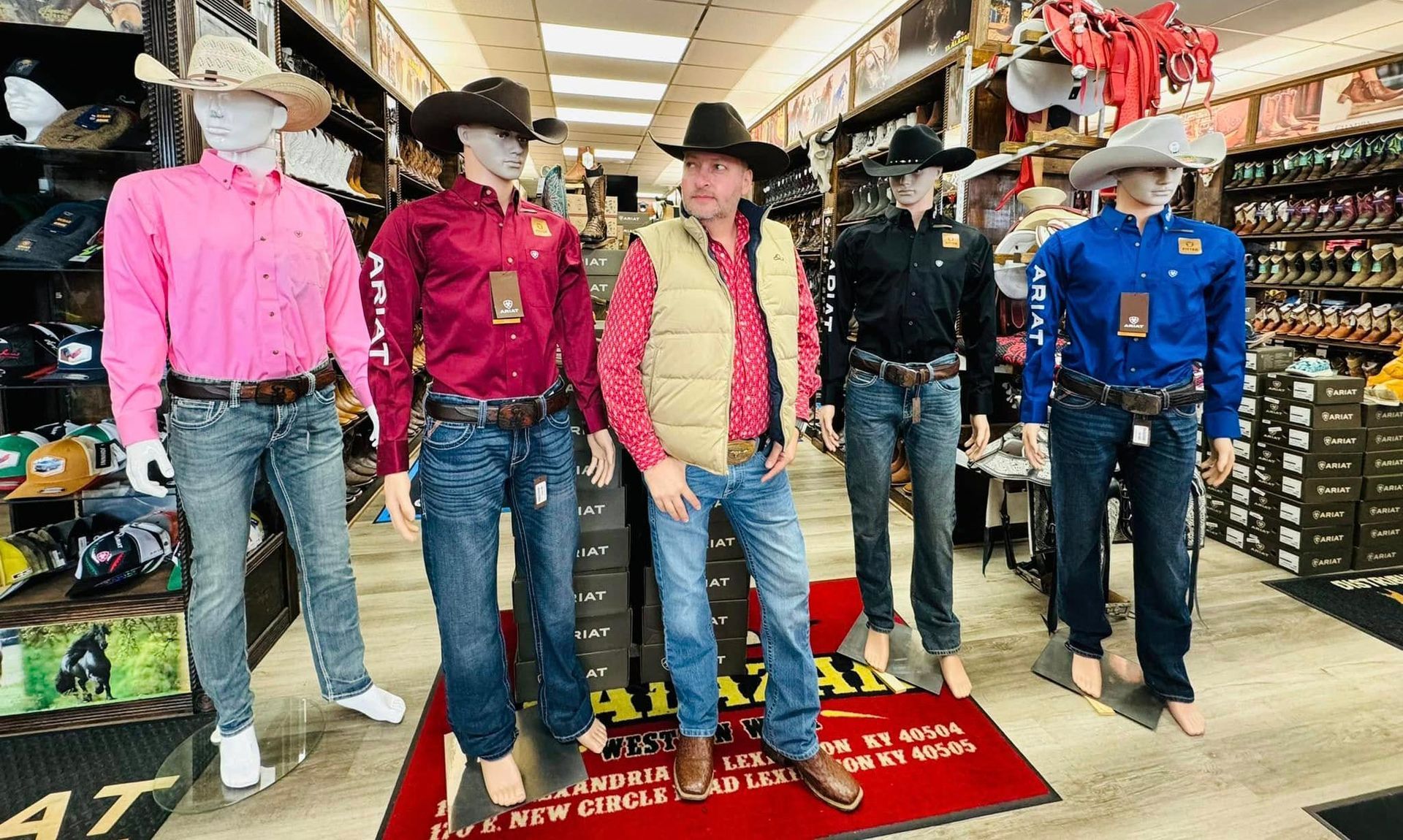 A man in a cowboy hat is standing next to a group of mannequins in a store.