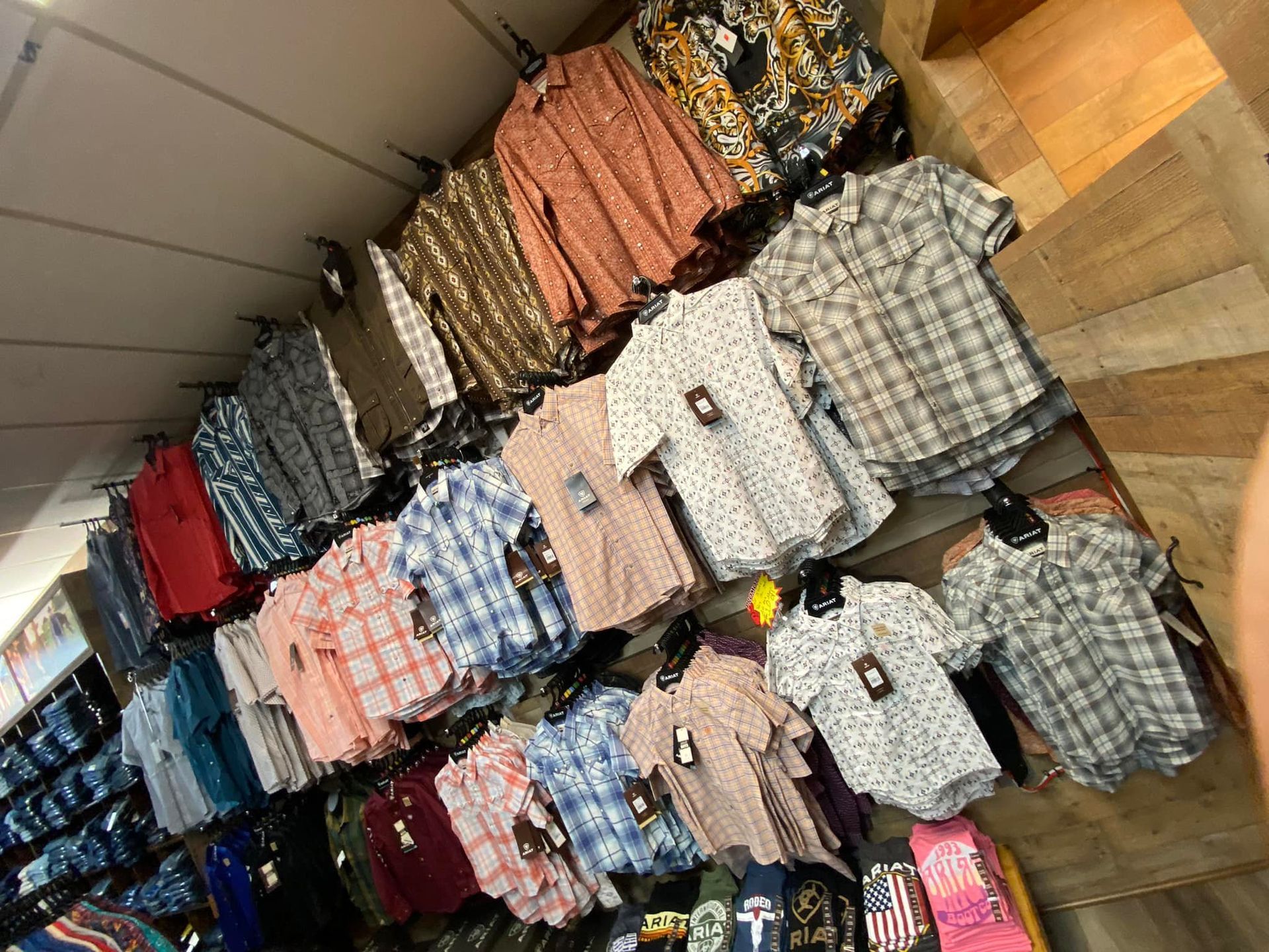 A bunch of shirts are hanging on a wall in a store.
