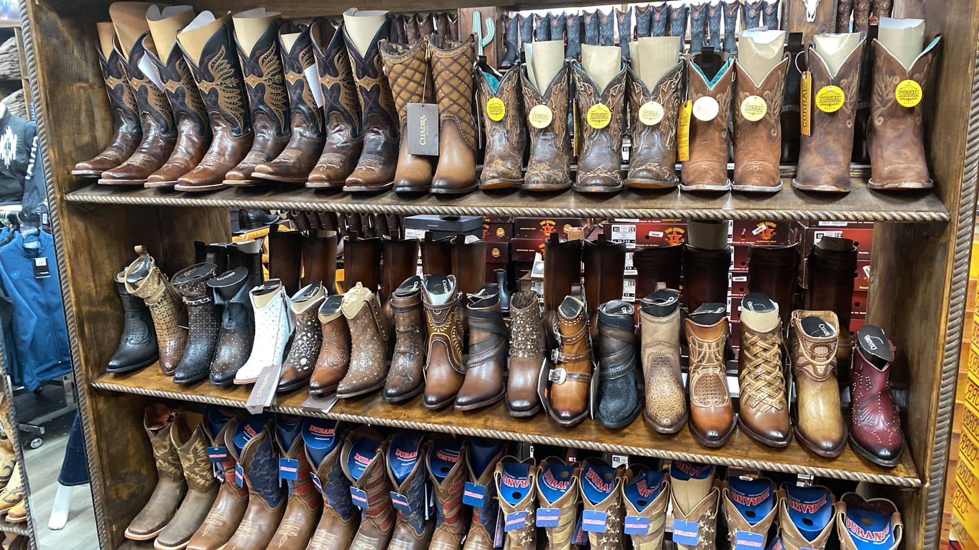 A shelf filled with lots of cowboy boots in a store.