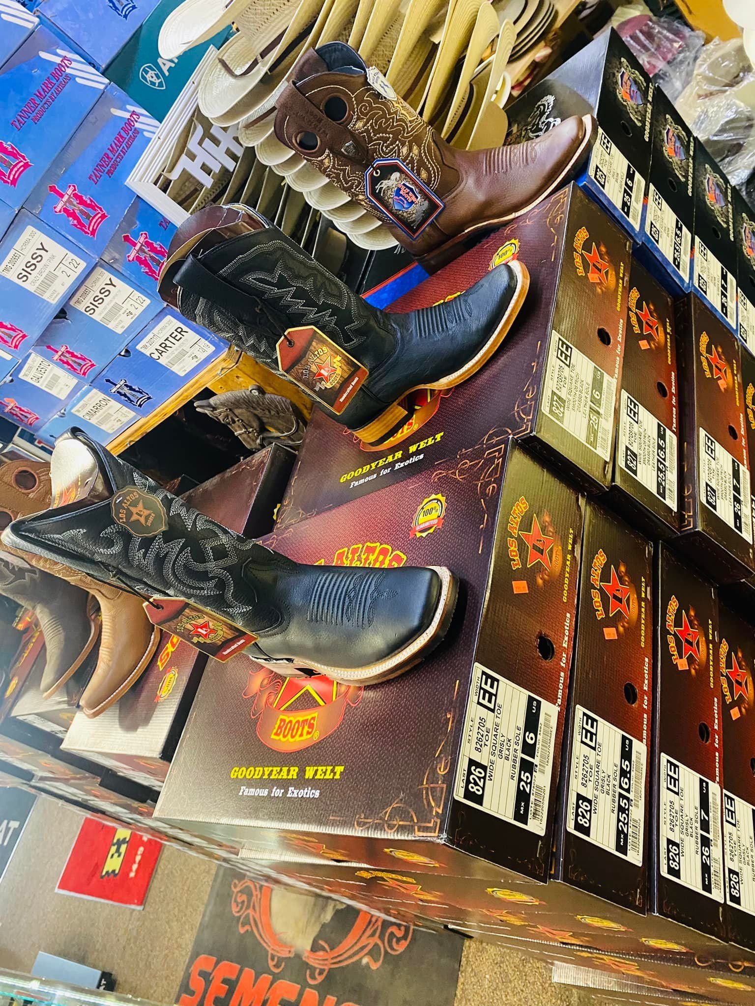 A bunch of cowboy boots are sitting on top of each other in boxes.