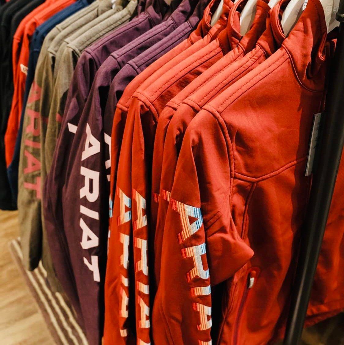 A row of red ariat jackets hanging on a rack