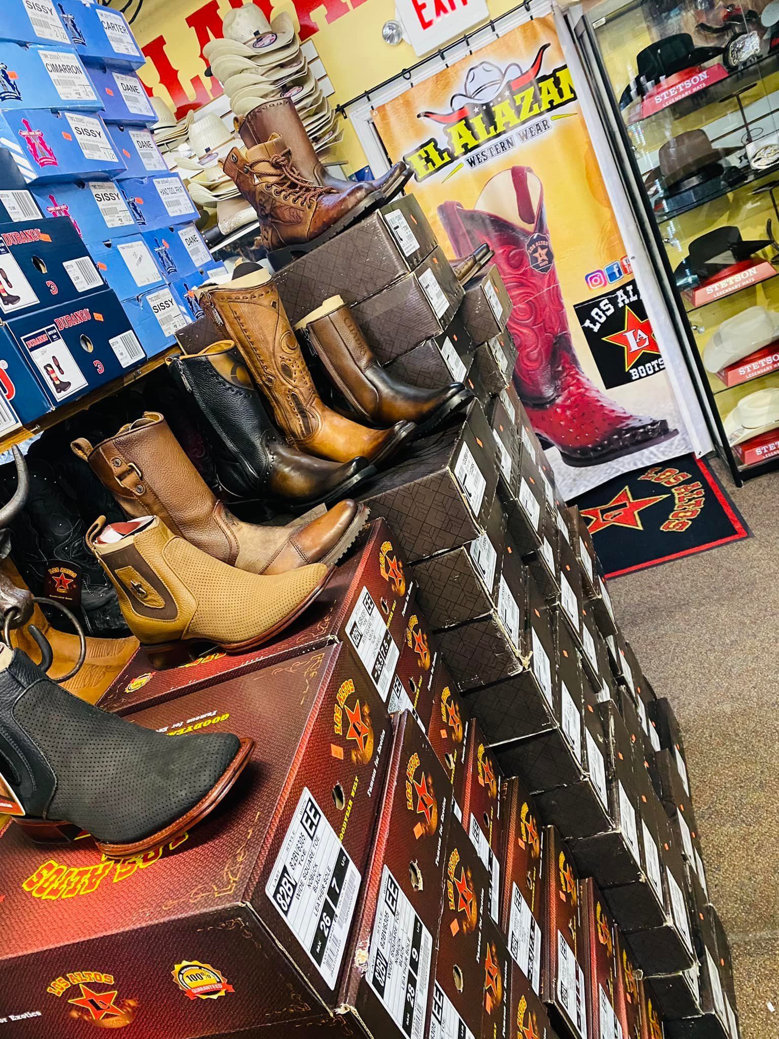 A bunch of cowboy boots are sitting on top of boxes in a store.