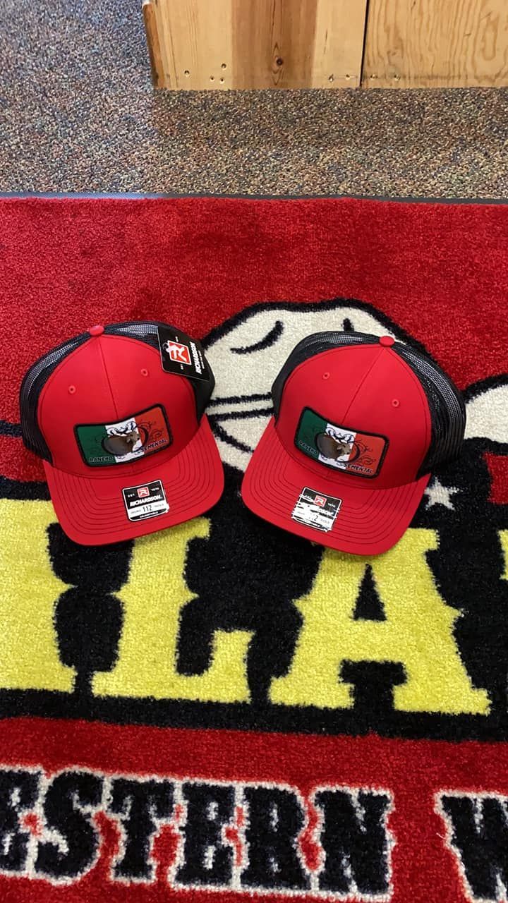 Two red hats are sitting on a rug that says western way