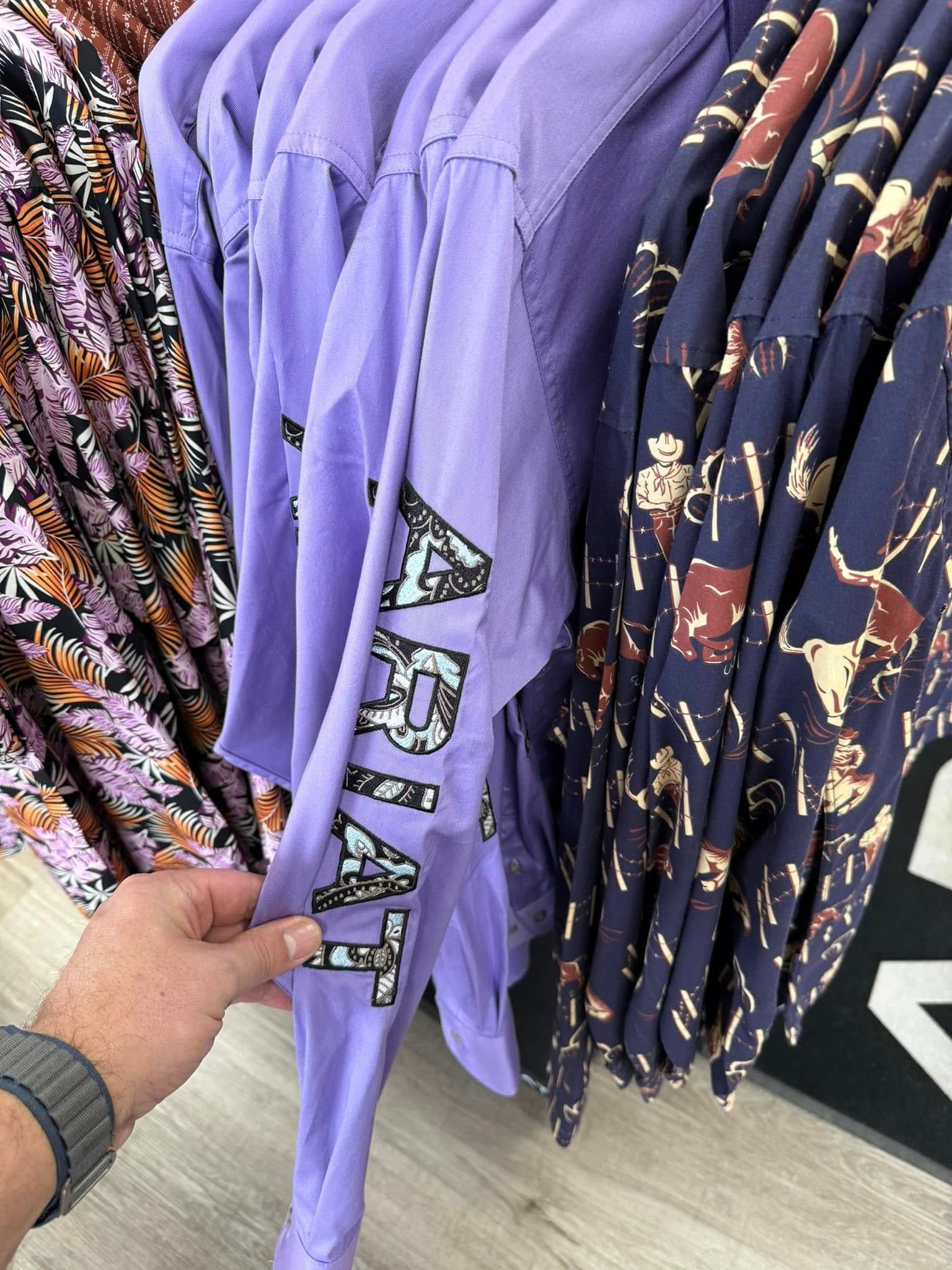 A person is holding a purple shirt with the word arizona on it.