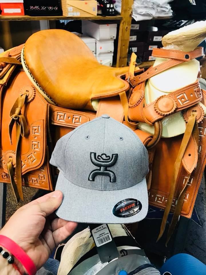 A person is holding a hat in front of a saddle.