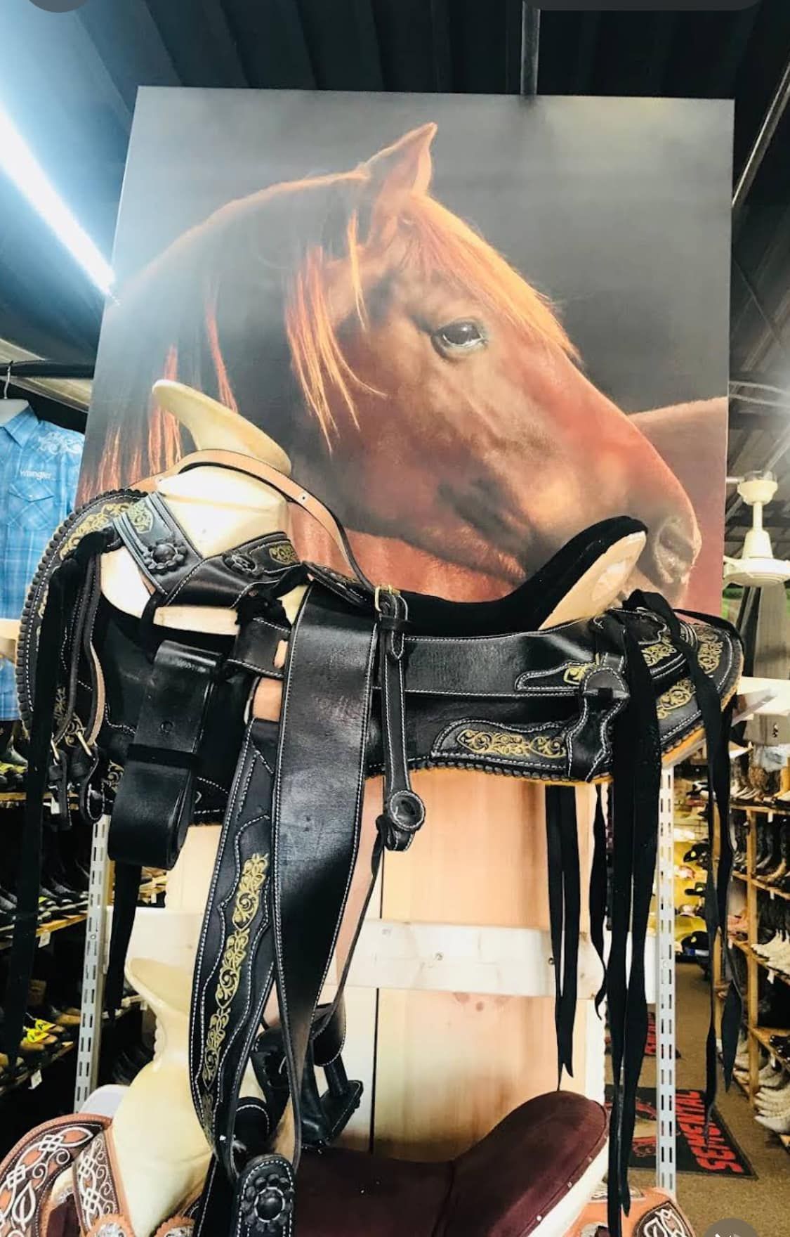 A horse saddle is sitting in front of a painting of a horse.