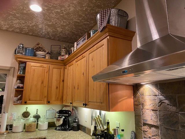 A kitchen with wooden cabinets and a stainless steel hood