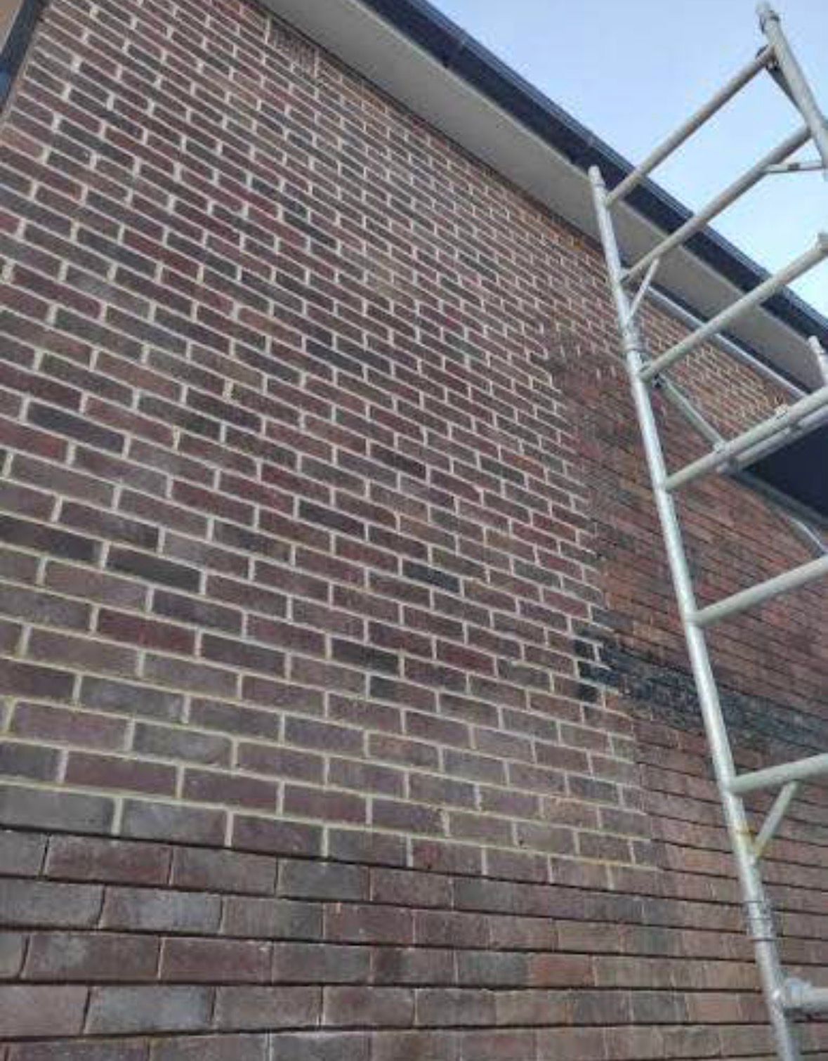 Brick house wall with metal scaffolding on the right side