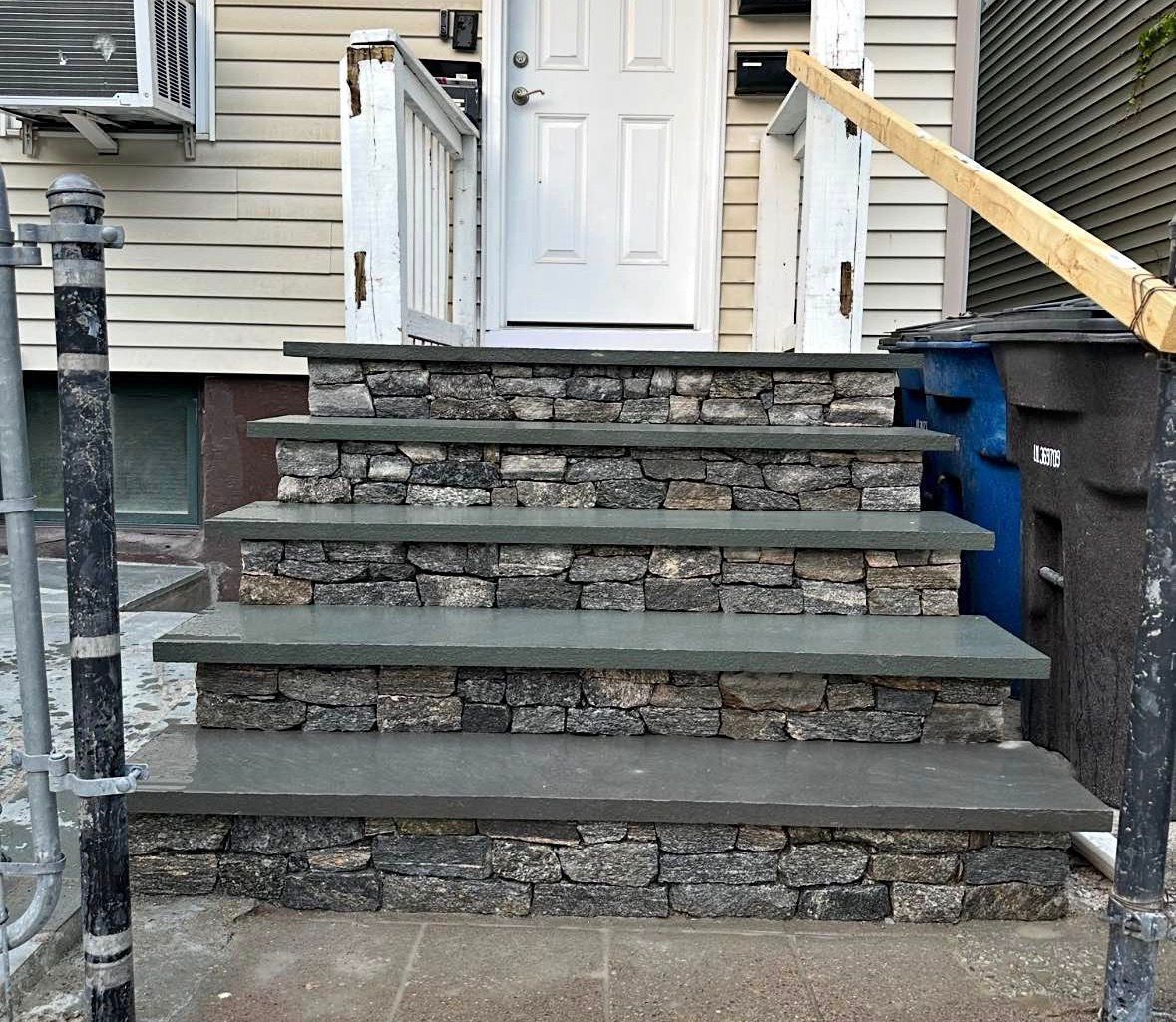 Front steps with six dark wooden treads leading to a white door on a house exterior