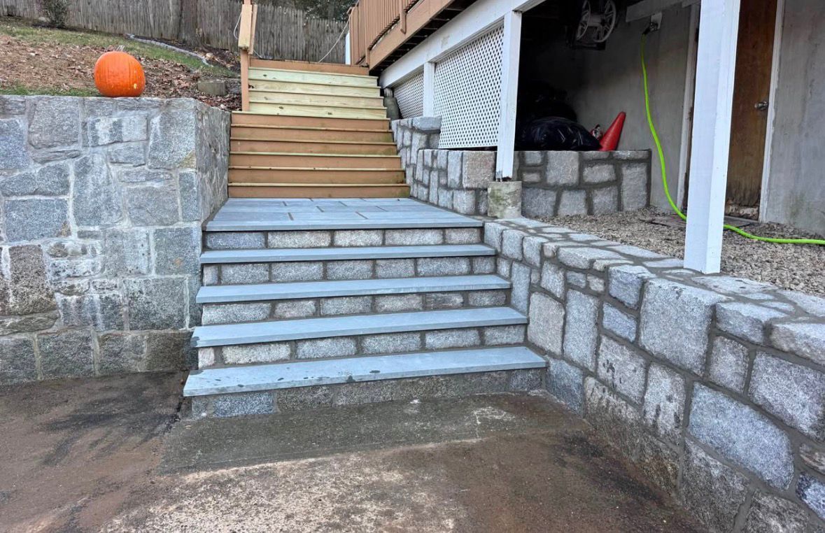 Stone steps leading to a wooden deck between stone retaining walls, with an orange ball on the left wall.