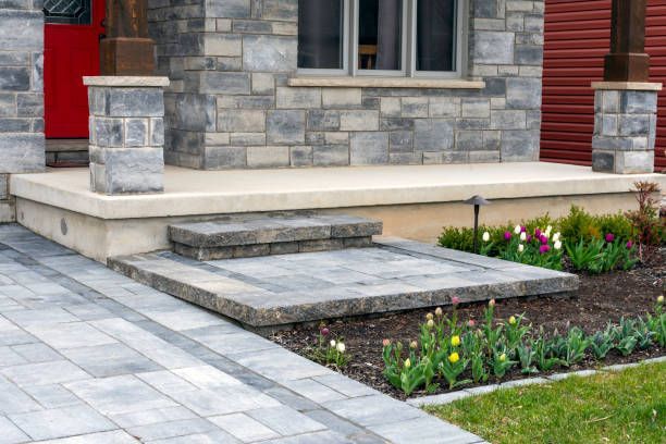 Stone house entrance with front steps, ramp, and flower bed by a paved walkway