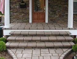 Front steps with a cracked, uneven stone walkway leading to a house entrance