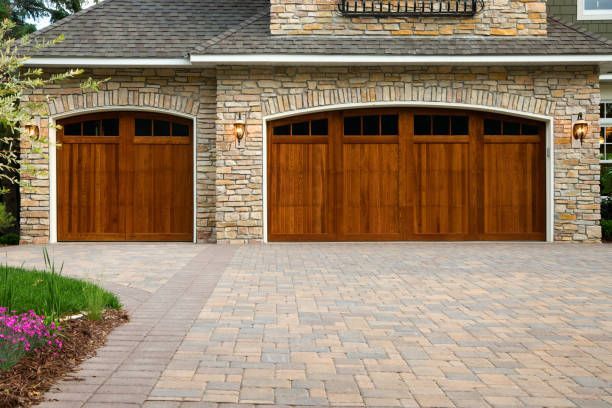 Stone house with two wooden garage doors and a paved driveway