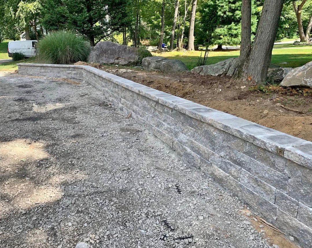Gravel road under construction beside a concrete curb in a wooded park area