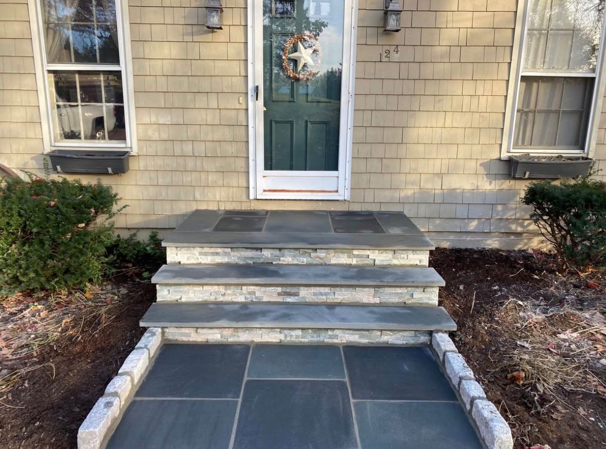 Front entrance with stone steps, teal door, and a dark tiled landing.