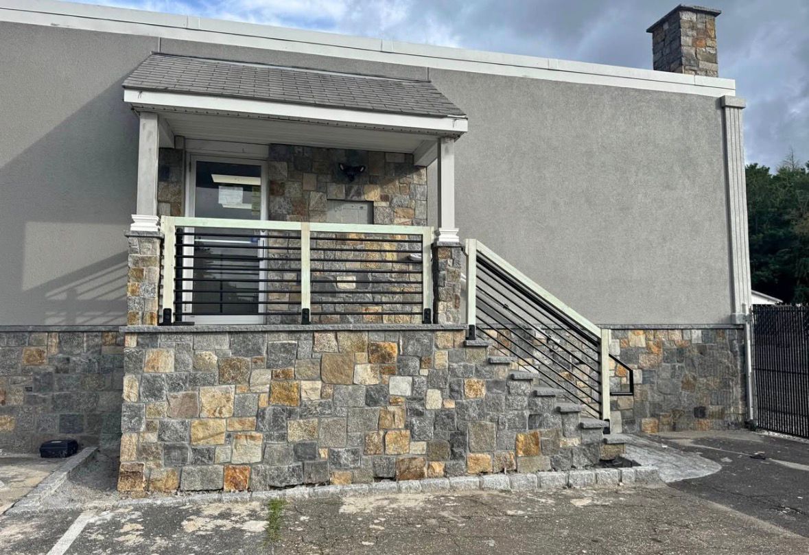 Stone-front house exterior with a small porch, white awning, and stairs leading to the entrance