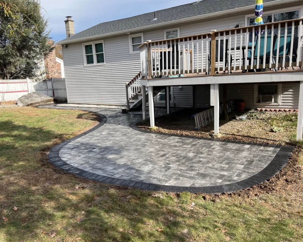 Backyard patio with curved stone path and raised wooden deck attached to a house