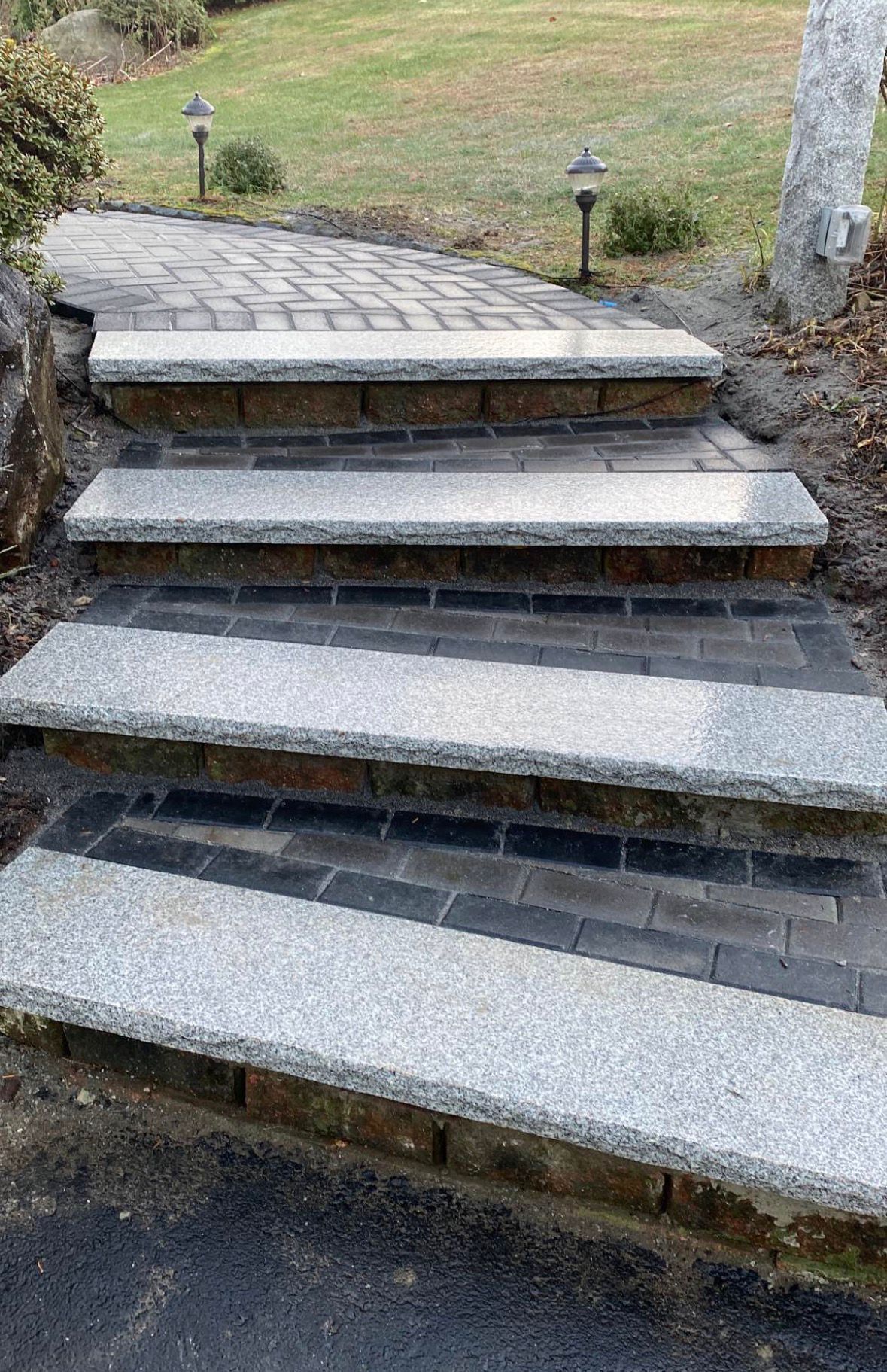 Stone steps leading up a grassy path with small black lanterns on either side