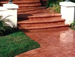 Red tiled steps leading up from a wet terracotta walkway, bordered by white pillars and green grass