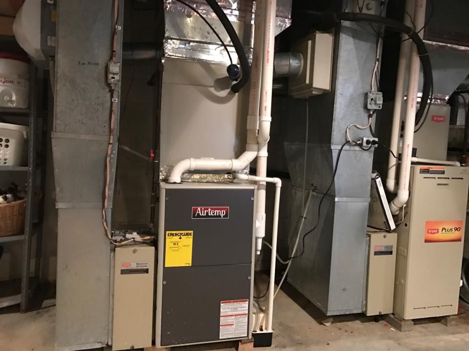 Two HVAC furnace units with attached metal ductwork and white PVC piping installed in a basement.