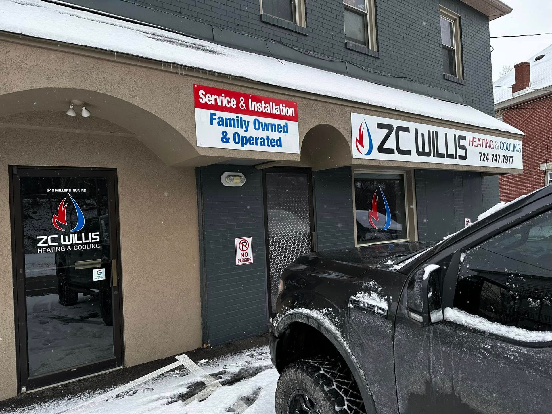 The storefront of ZC Willis heating and cooling services, featuring signage and a parked truck in a snowy setting.