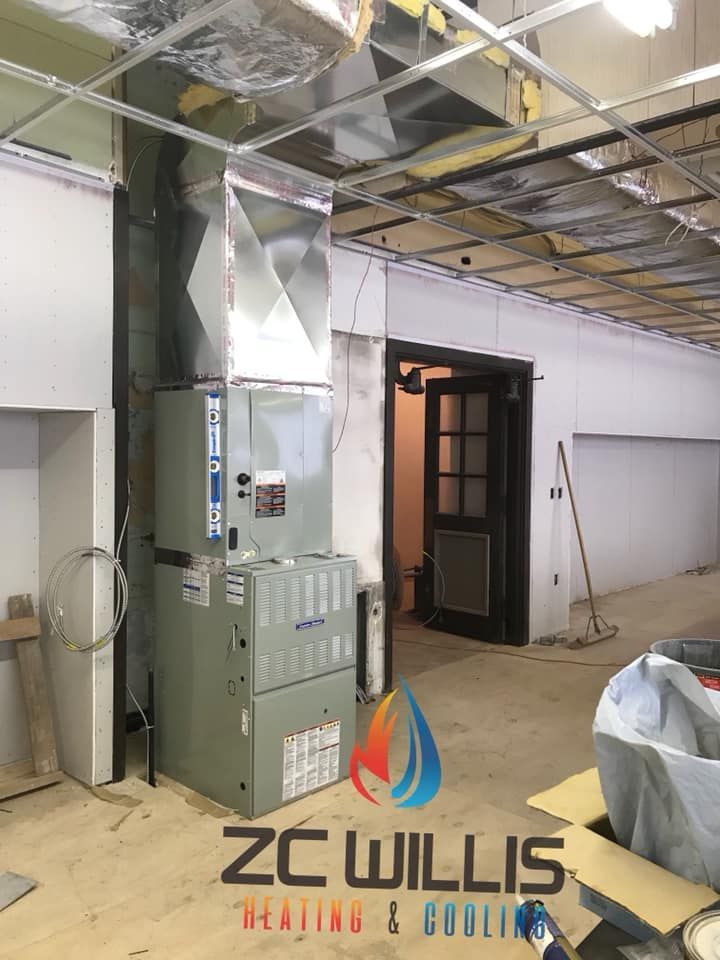 A new HVAC unit and silver metal ductwork installed in a room under construction, with a ZC Willis logo at the bottom.