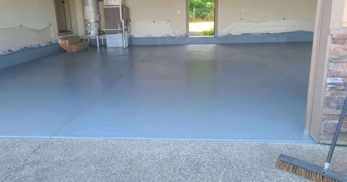 a garage with a gray floor and a broom