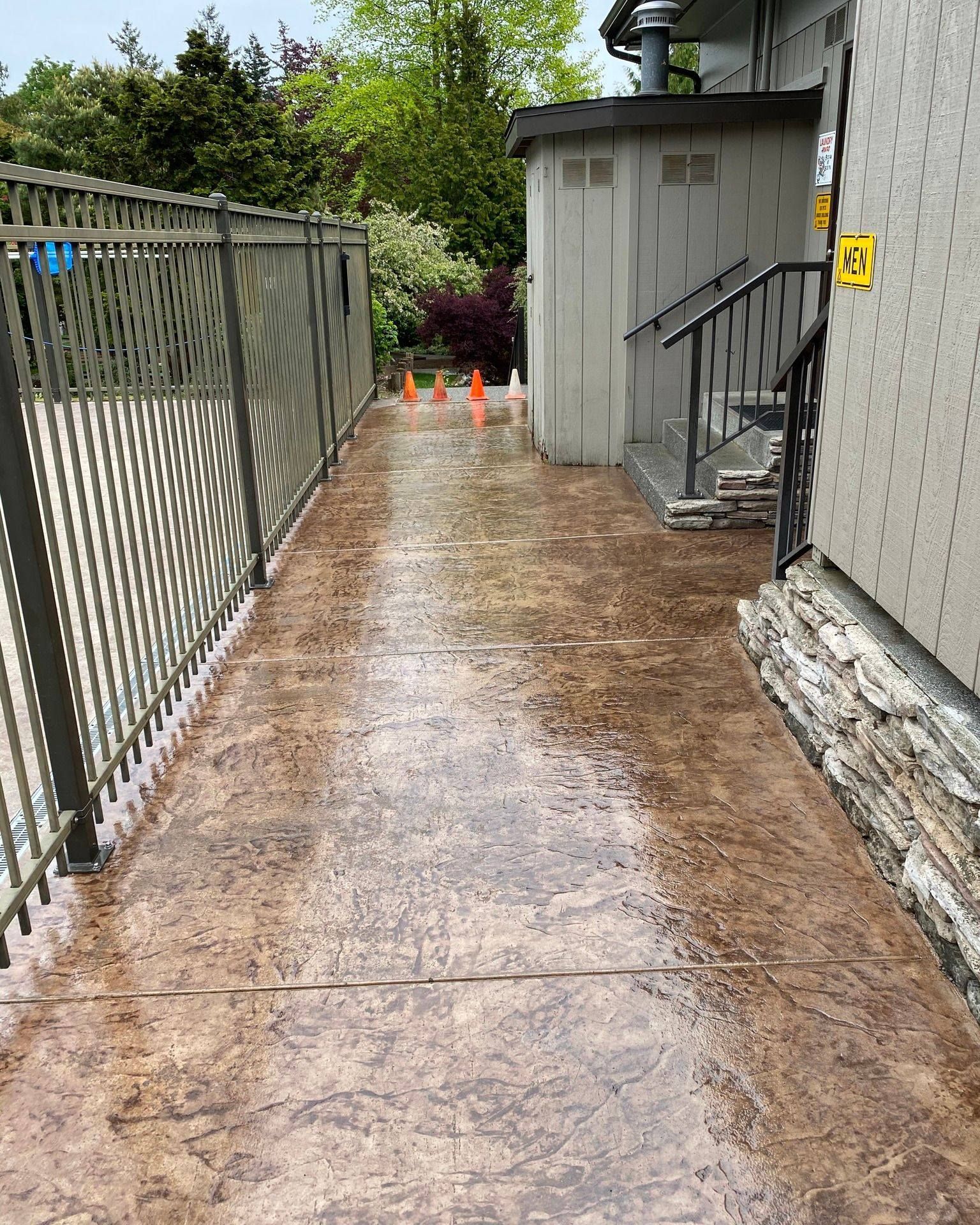 a concrete walkway leading to a building with a fence