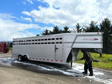 a man is washing a horse trailer with a high pressure washer .