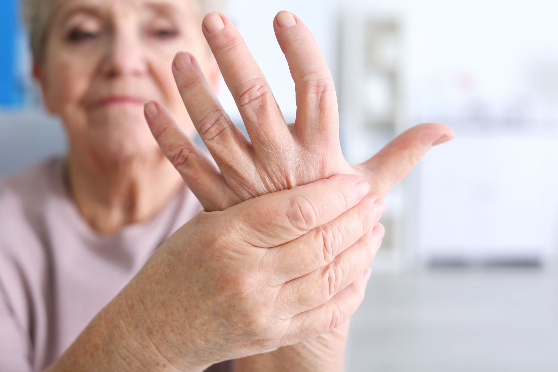 An elderly woman is holding her hand in pain.