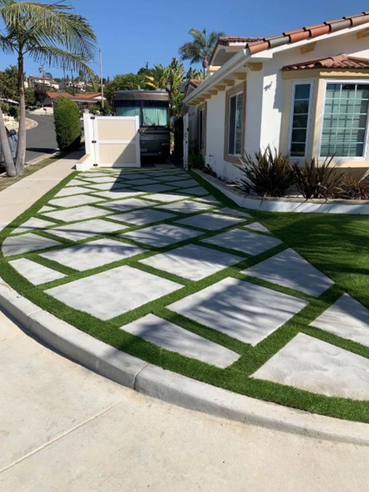 A white house with a concrete driveway surrounded by green grass